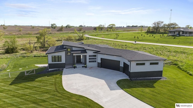 view of front of house featuring a front lawn, fence, a rural view, concrete driveway, and an attached garage