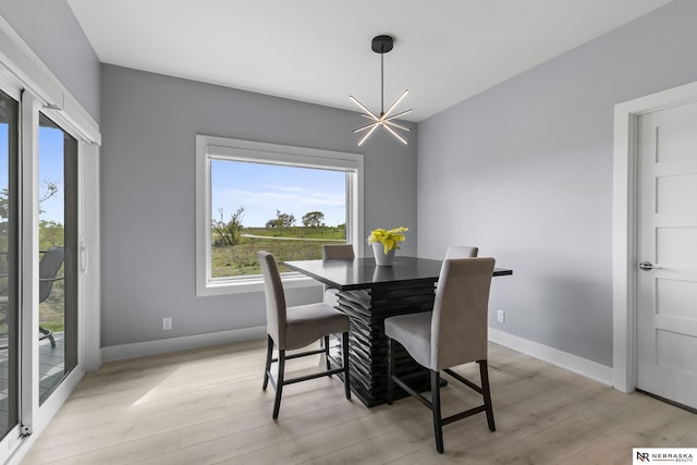 dining room with light wood-type flooring, baseboards, and a chandelier