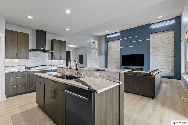 kitchen with wall chimney range hood, a sink, dishwasher, light wood-style flooring, and modern cabinets