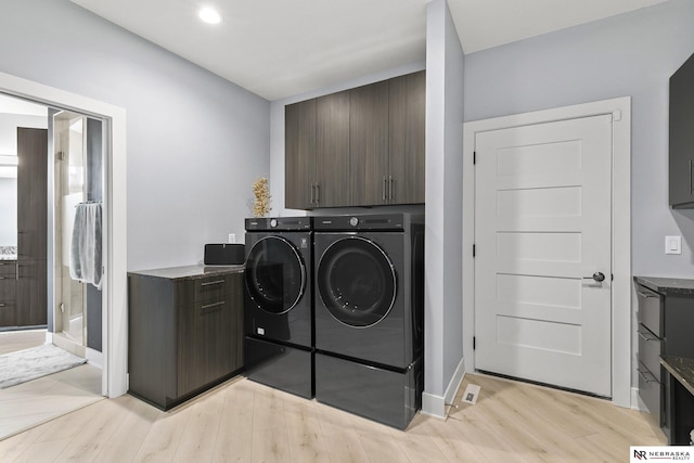 laundry room with light wood-style floors, baseboards, cabinet space, and washing machine and clothes dryer