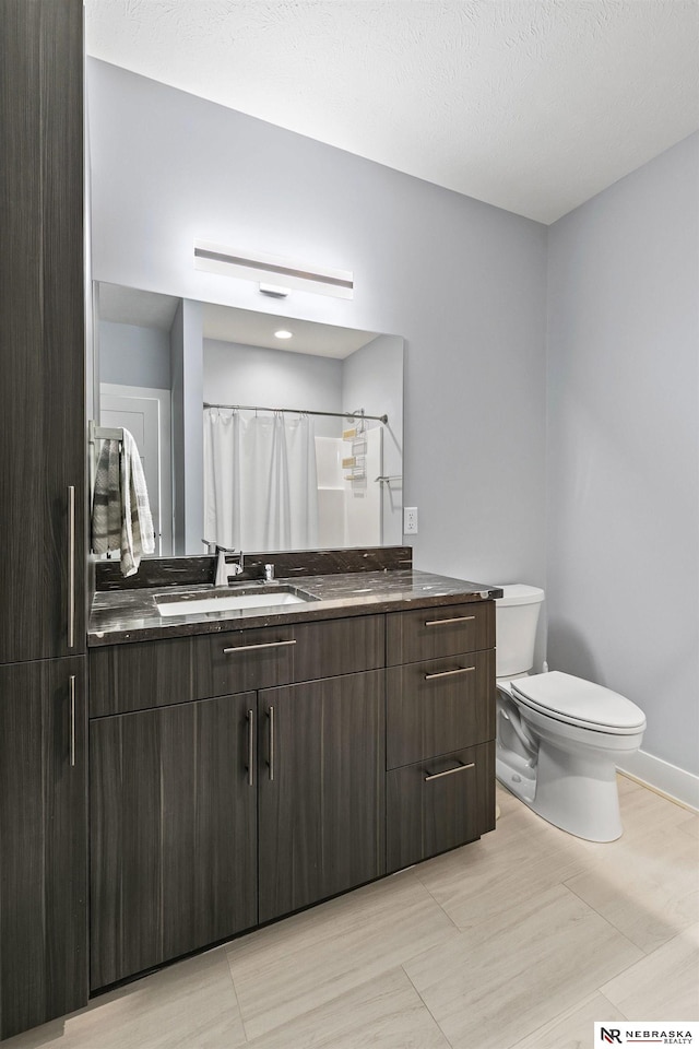 full bath with vanity, baseboards, and toilet