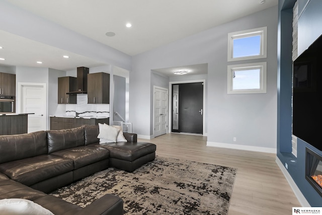 living area with baseboards, recessed lighting, and light wood-style flooring