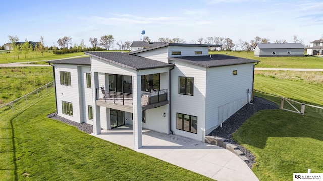 back of house featuring a shingled roof, a patio area, a balcony, and a yard