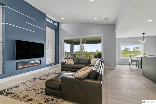 living room with a glass covered fireplace, recessed lighting, light wood-style flooring, and a notable chandelier