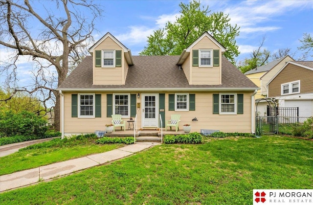 new england style home featuring fence, a shingled roof, and a front lawn
