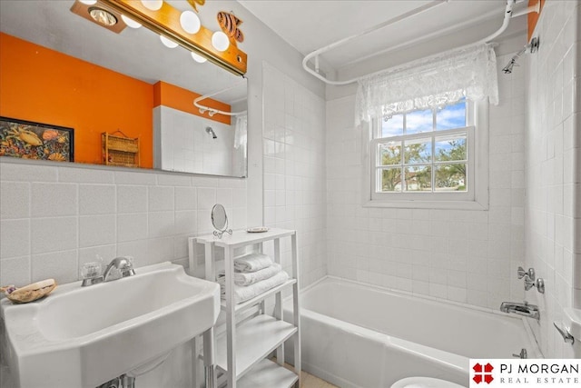 full bath with  shower combination, tile walls, a sink, and tasteful backsplash