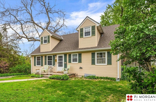 cape cod home featuring a shingled roof and a front lawn