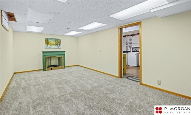 finished basement featuring a fireplace, baseboards, washer / clothes dryer, a drop ceiling, and carpet flooring