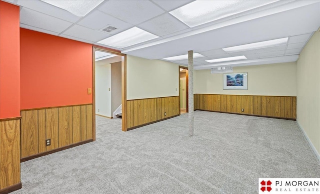 finished below grade area with carpet floors, wooden walls, a paneled ceiling, and a wainscoted wall