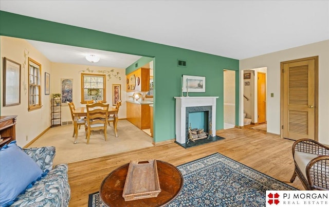 living room with baseboards, visible vents, and light wood finished floors