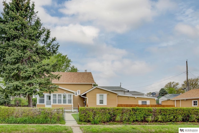 bungalow-style home with a shingled roof, a gate, and fence