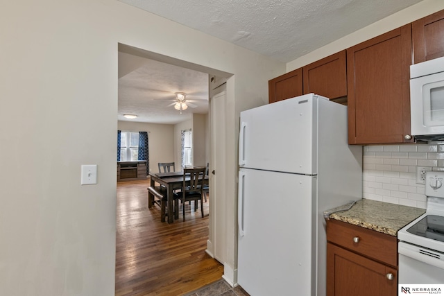 kitchen with white appliances, tasteful backsplash, brown cabinets, ceiling fan, and dark wood-style floors