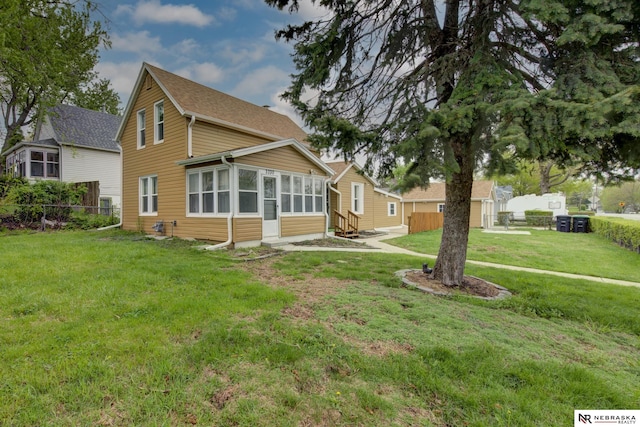 rear view of house featuring a sunroom, fence, and a lawn
