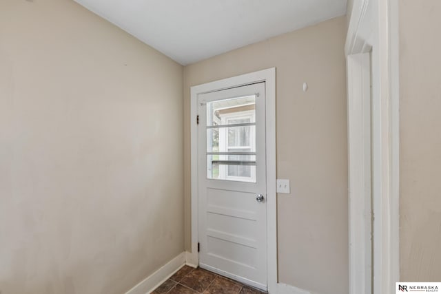 entryway with baseboards and dark tile patterned floors
