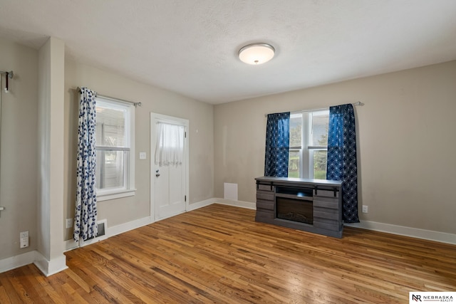 foyer entrance featuring visible vents, wood finished floors, baseboards, and a fireplace