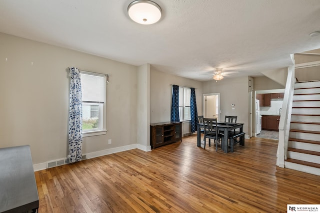 dining space with stairs, visible vents, baseboards, ceiling fan, and hardwood / wood-style flooring