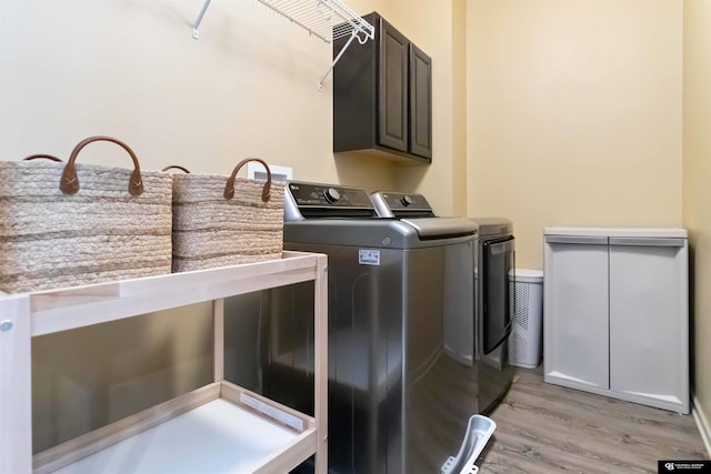 laundry area featuring separate washer and dryer, light wood finished floors, and cabinet space