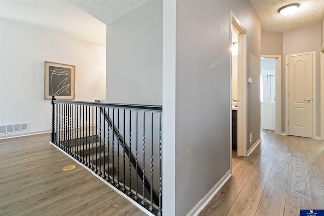 hall featuring an upstairs landing, wood finished floors, and baseboards