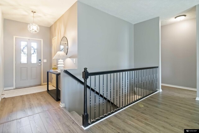 foyer entrance featuring wood finished floors, baseboards, and a chandelier