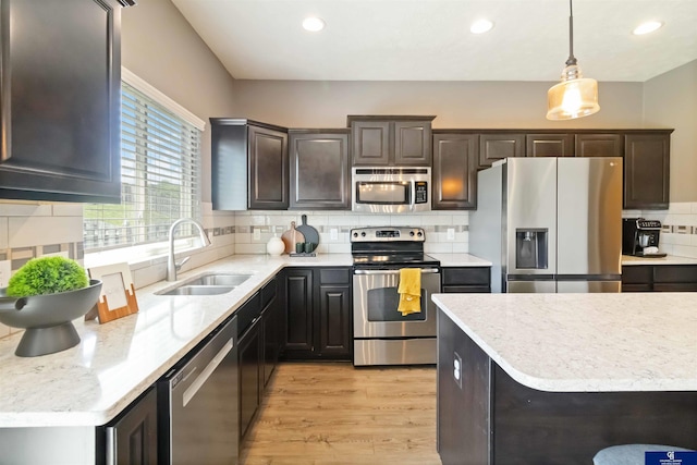 kitchen with stainless steel appliances, a sink, recessed lighting, light wood-style flooring, and backsplash