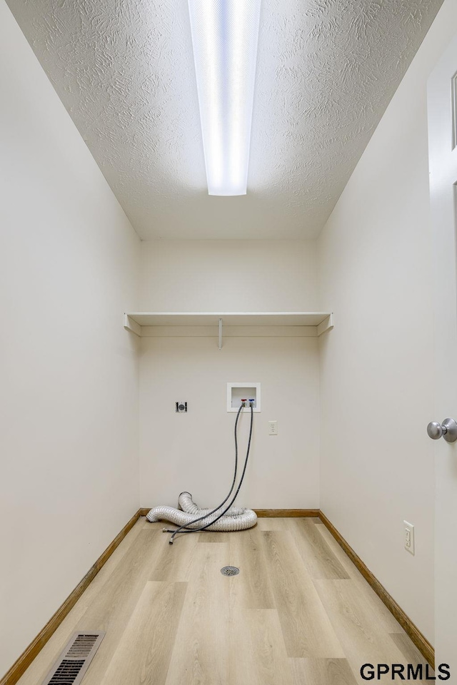 clothes washing area featuring laundry area, wood finished floors, baseboards, a textured ceiling, and washer hookup