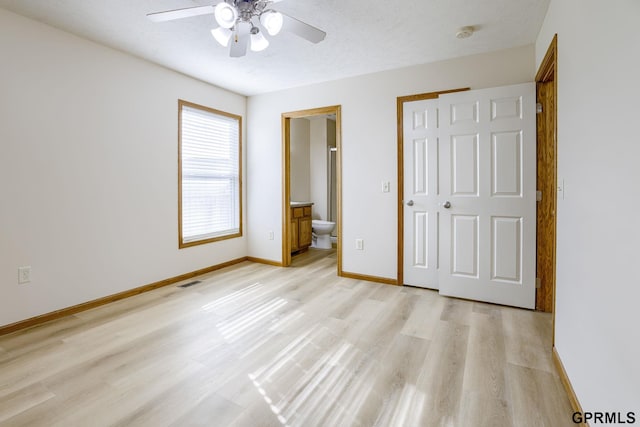 unfurnished bedroom with ensuite bath, light wood-style flooring, a ceiling fan, baseboards, and visible vents