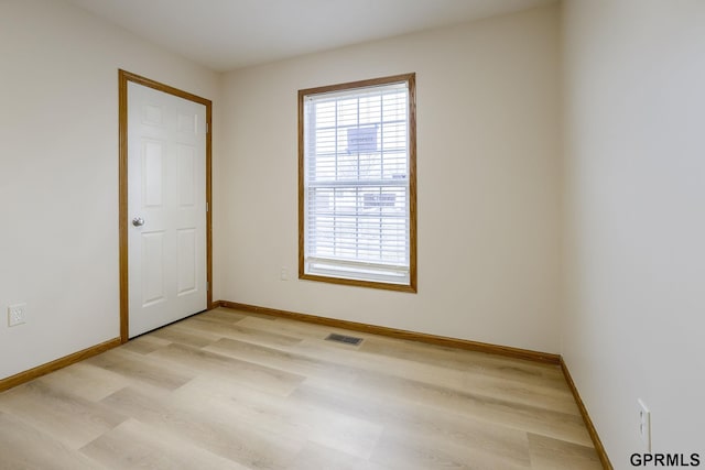 empty room featuring light wood-style floors, plenty of natural light, and visible vents