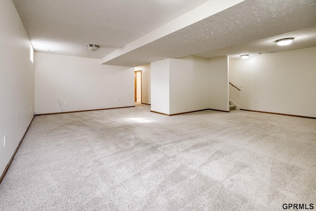 finished below grade area with baseboards, a textured ceiling, carpet, and stairs