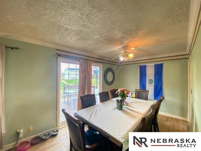 dining space featuring baseboards, a textured ceiling, and wood finished floors