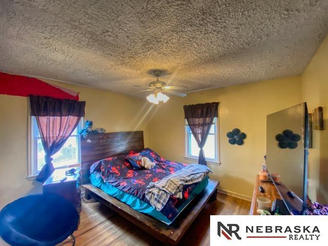 bedroom with a textured ceiling, ceiling fan, and wood finished floors