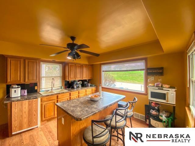kitchen with a sink, brown cabinets, light wood-type flooring, and a kitchen bar
