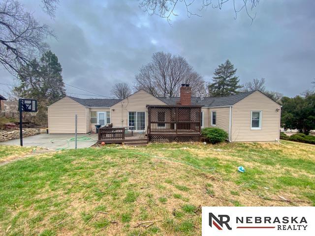 rear view of property with a yard, a deck, and a chimney