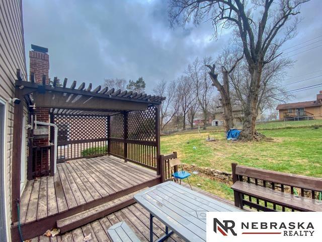 wooden terrace featuring a yard, a pergola, and fence