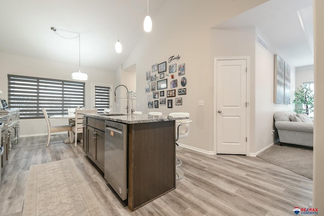 kitchen featuring stainless steel dishwasher, visible vents, baseboards, a sink, and light wood finished floors