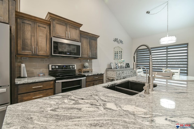 kitchen featuring decorative backsplash, appliances with stainless steel finishes, a sink, high vaulted ceiling, and light stone counters