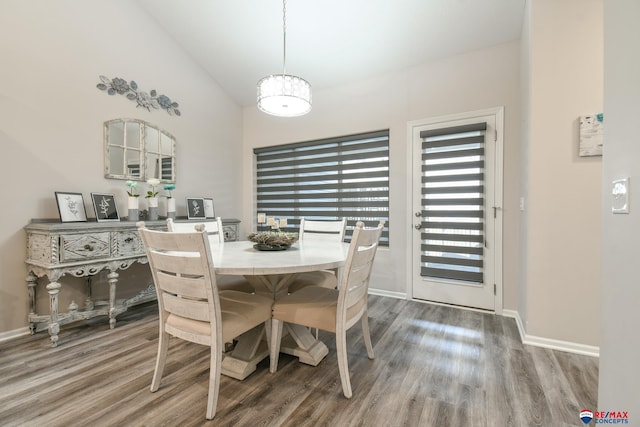 dining space featuring baseboards, wood finished floors, a healthy amount of sunlight, and high vaulted ceiling