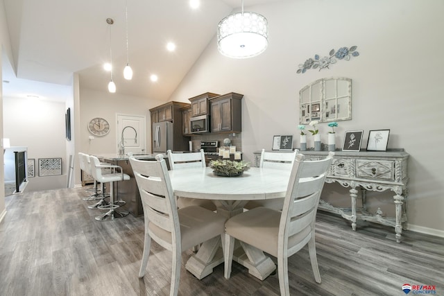 dining room with baseboards, high vaulted ceiling, and wood finished floors