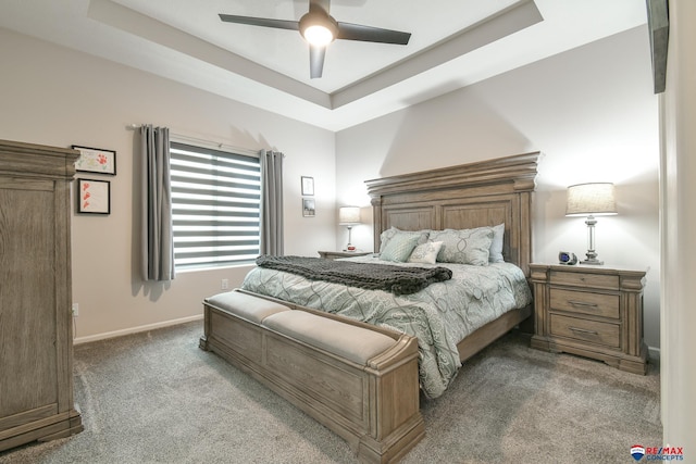 bedroom with a raised ceiling, baseboards, carpet, and ceiling fan