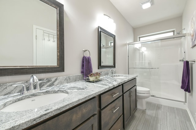 full bath featuring a sink, a stall shower, toilet, and double vanity