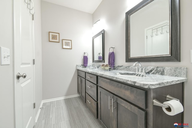 full bath featuring double vanity, a sink, and baseboards