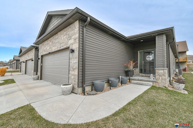 view of home's exterior with a lawn, central AC unit, a garage, concrete driveway, and stone siding