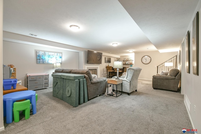living room featuring visible vents, a fireplace, stairway, a textured ceiling, and carpet
