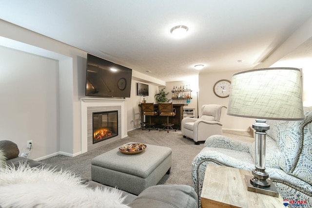 carpeted living room featuring baseboards, a tiled fireplace, and a bar