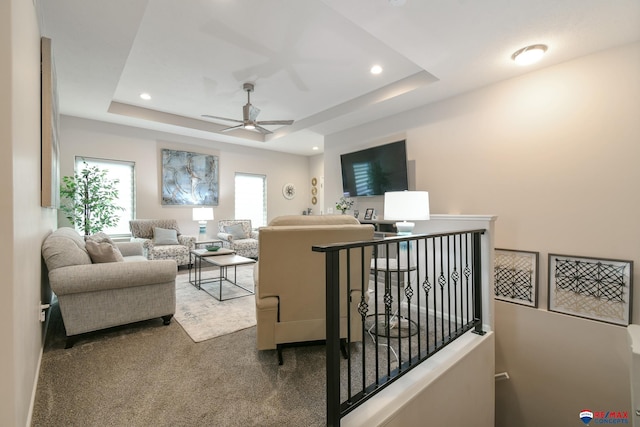 living area with a raised ceiling, ceiling fan, carpet flooring, and recessed lighting