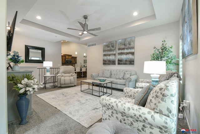 carpeted living area with a raised ceiling, ceiling fan, recessed lighting, and visible vents