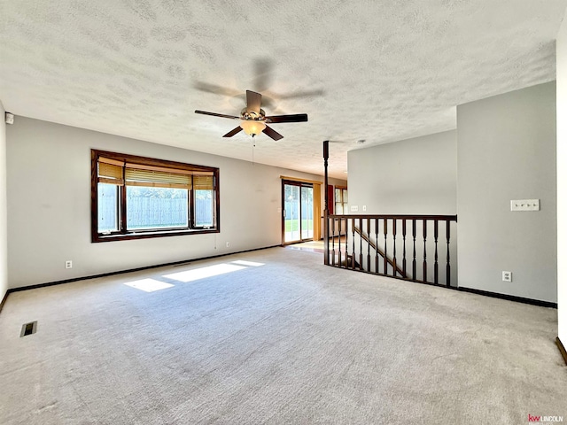 carpeted empty room featuring ceiling fan, a textured ceiling, baseboards, and visible vents
