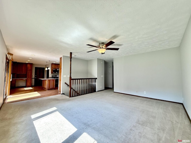 unfurnished living room featuring a textured ceiling, light carpet, baseboards, and ceiling fan