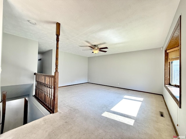 unfurnished room with a ceiling fan, a textured ceiling, baseboards, carpet flooring, and visible vents