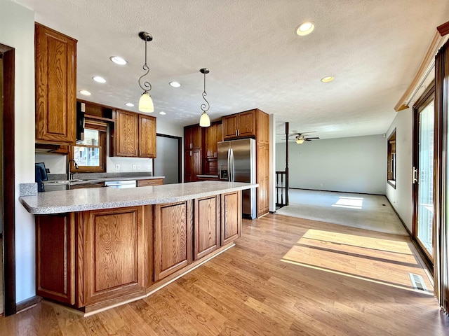kitchen featuring recessed lighting, a peninsula, light wood finished floors, and appliances with stainless steel finishes