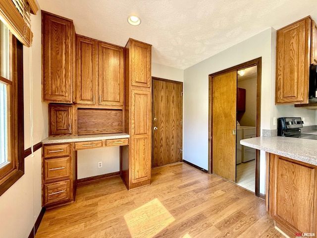 interior space featuring brown cabinetry, built in study area, stainless steel range with electric stovetop, light countertops, and light wood-type flooring